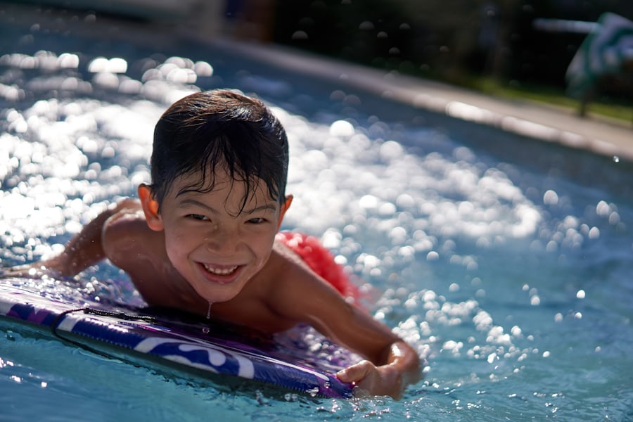 Lachender Junge auf einem Schwimmbrett