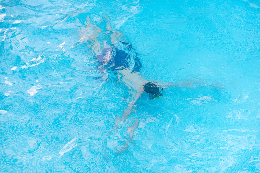Kind gleitet unter Wasser durchs Becken